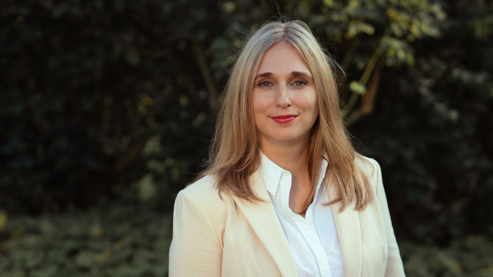 Professional portrait of a woman in a business suit, looking confident and polished in a studio setting.