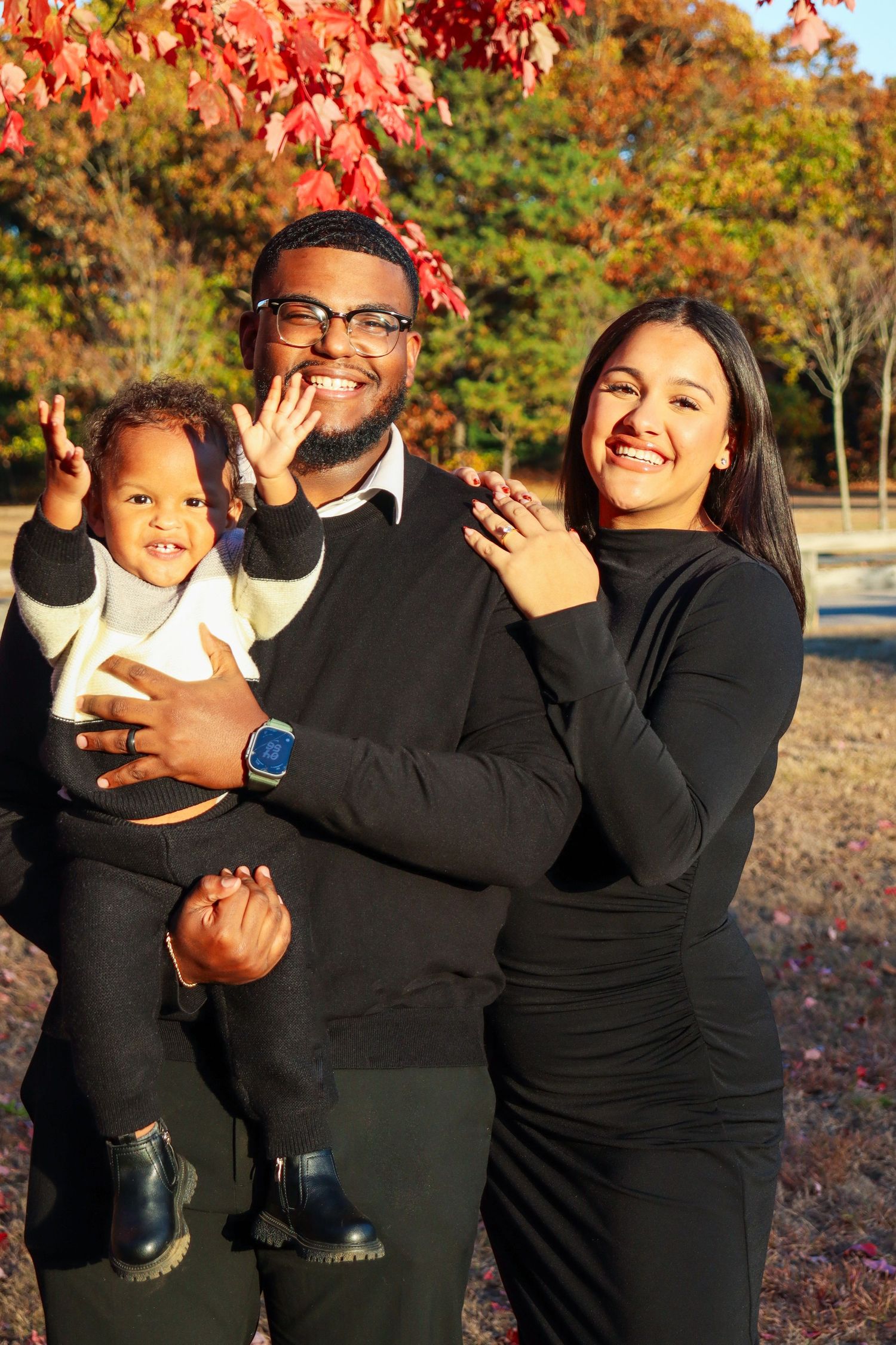 Happy family enjoying autumn day amongst red fall foliage.