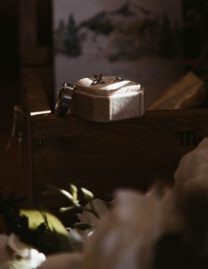 Wedding rings rest on a vintage wooden surface in moody lighting.