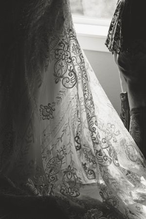 Close-up black and white detail of intricate lace patterns on a wedding dress.