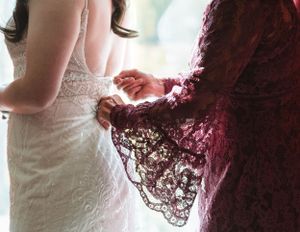 Close-up detail of burgundy lace against a white wedding dress.