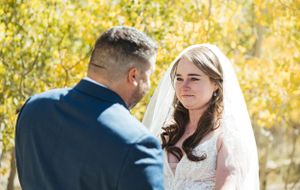 A couple shares an intimate moment in golden autumn sunlight with yellow foliage in the background.