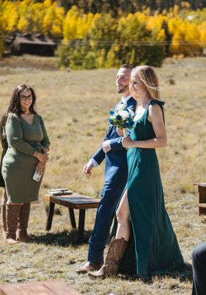 Wedding party members walk through golden autumn field during outdoor ceremony.