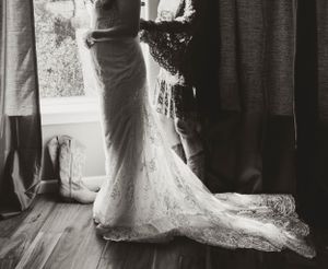 Close-up black and white photograph of a wedding dress train flowing on hardwood floor.