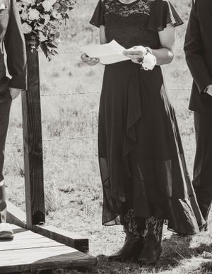 Black and white photo of wedding ceremony participants holding papers outdoors.