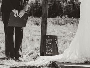 Black and white photo of wedding ceremony details with flowing white dress.