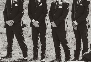 Black and white photo showing groomsmen in matching tuxedos standing in a row.