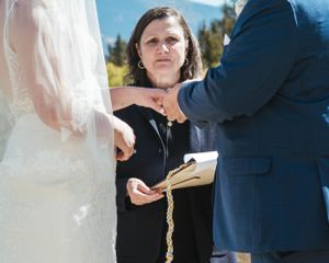 An outdoor wedding ceremony in progress with attendees gathered under bright sunlight.