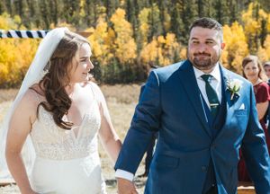 A joyful wedding couple shares a candid moment during their autumn outdoor ceremony.