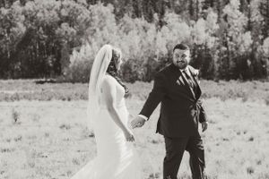 A black and white wedding photo captures a romantic moment between newlyweds in an outdoor field setting.
