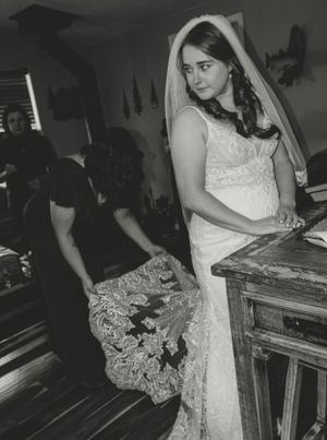 A black and white photo showing a wedding dress with intricate lace details.