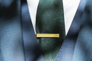 Close-up of navy suit with dark green tie and gold tie clip.