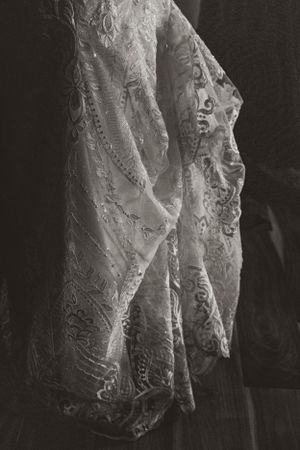 Close-up detail of intricate lace patterns on a wedding dress in black and white.
