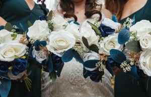 Wedding bouquets featuring white roses and navy blue flowers arranged together with delicate details.