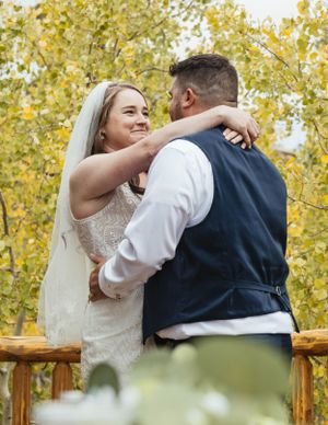 A couple embraces during an autumn wedding photoshoot with golden yellow foliage in the background.