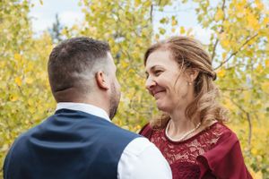 A couple shares a joyful moment together outdoors with golden autumn foliage in the background.
