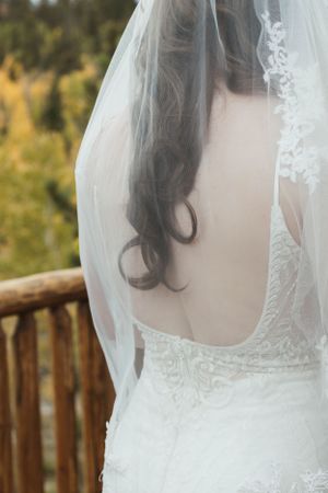 A close-up view of a delicate white wedding veil and lace dress detail against an autumn outdoor backdrop.
