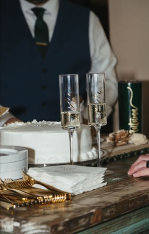 Elegant champagne glasses and table settings with gold utensils on a rustic wooden surface.
