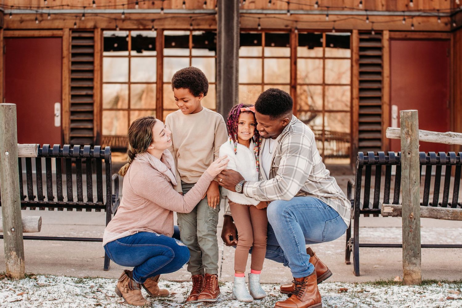 A family sharing a tender moment while sitting on a bench outside a rustic building.