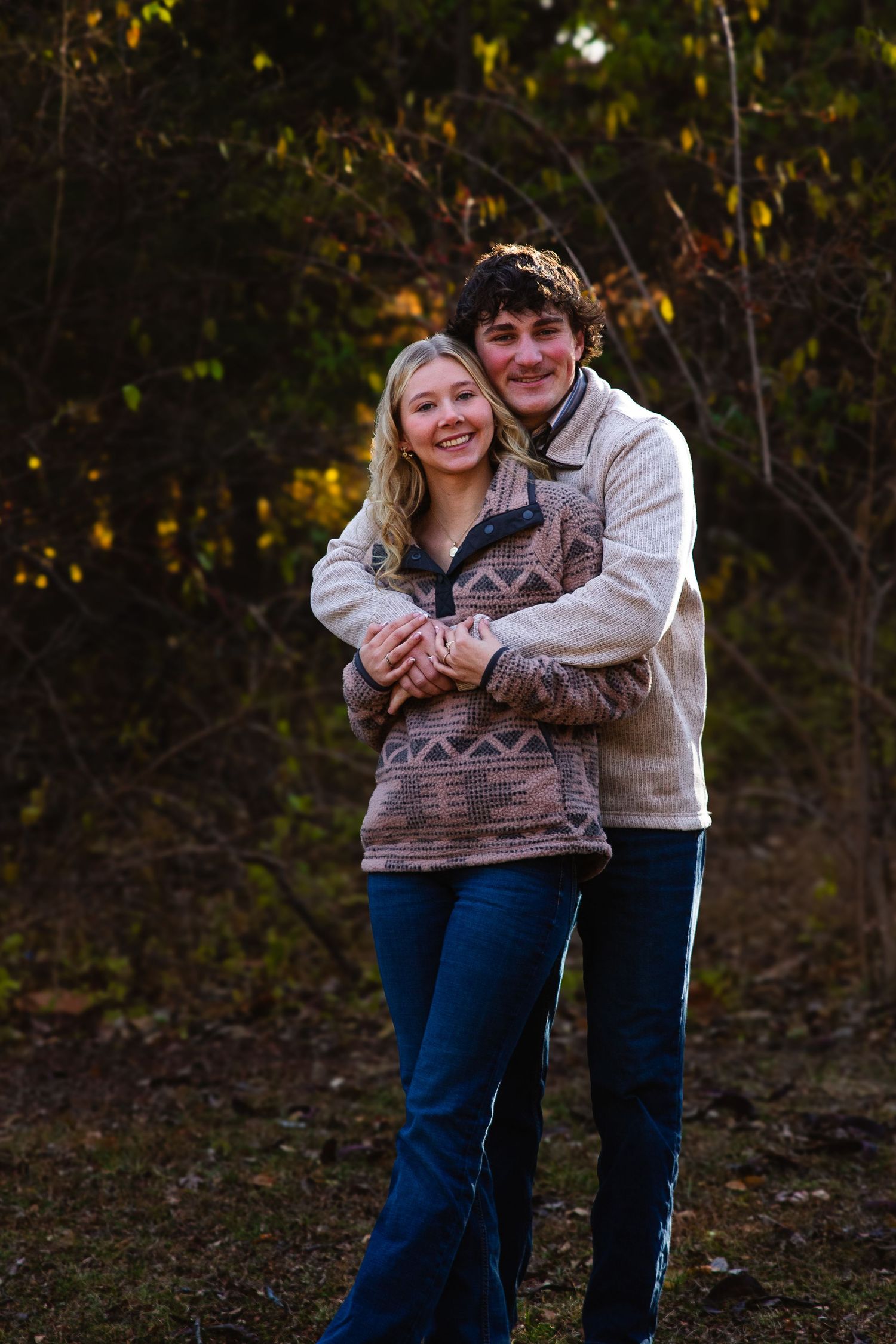 Happy couple in matching sweaters share a romantic moment outdoors.