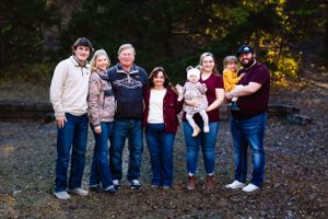 Extended family group poses together for a casual outdoor portrait in autumn.