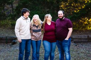 Four people share a candid moment together outdoors wearing coordinated casual attire.
