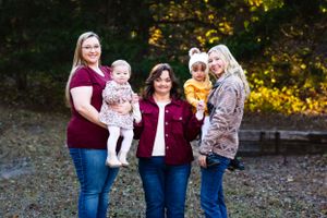 Group of five poses casually together outdoors wearing burgundy and neutral tones.