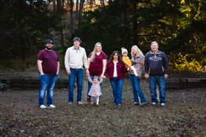 Family group lines up for a casual portrait against an autumn woodland backdrop.