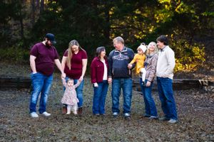 Multi-generational family group poses informally together outdoors during golden hour.
