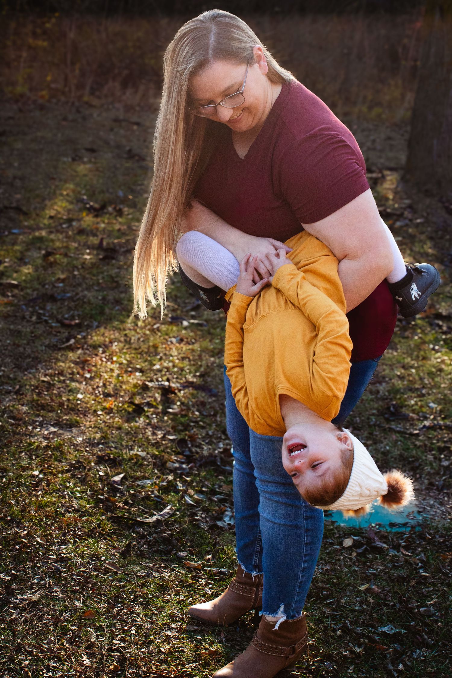 Playful moment between parent and child in casual attire outdoors during autumn.