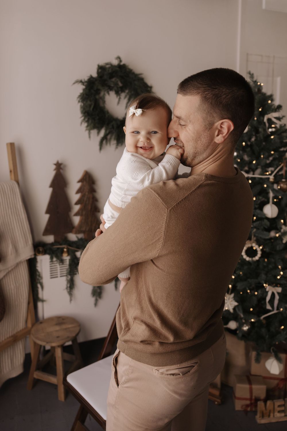 Tender family moment captured in warm tones near decorated Christmas tree.
