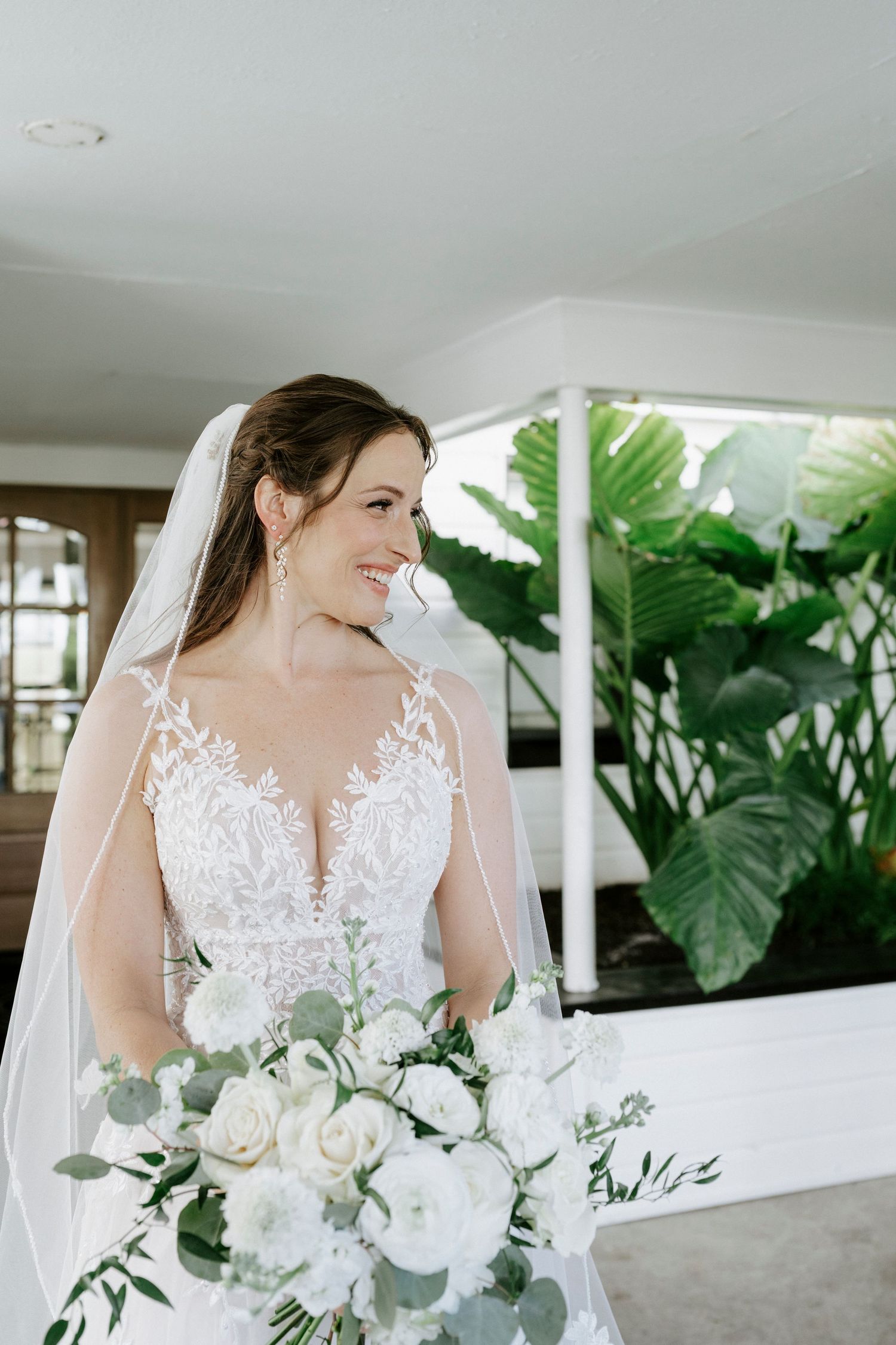 Beautiful bridal portrait with white lace wedding gown and elegant bouquet of white roses and greenery.