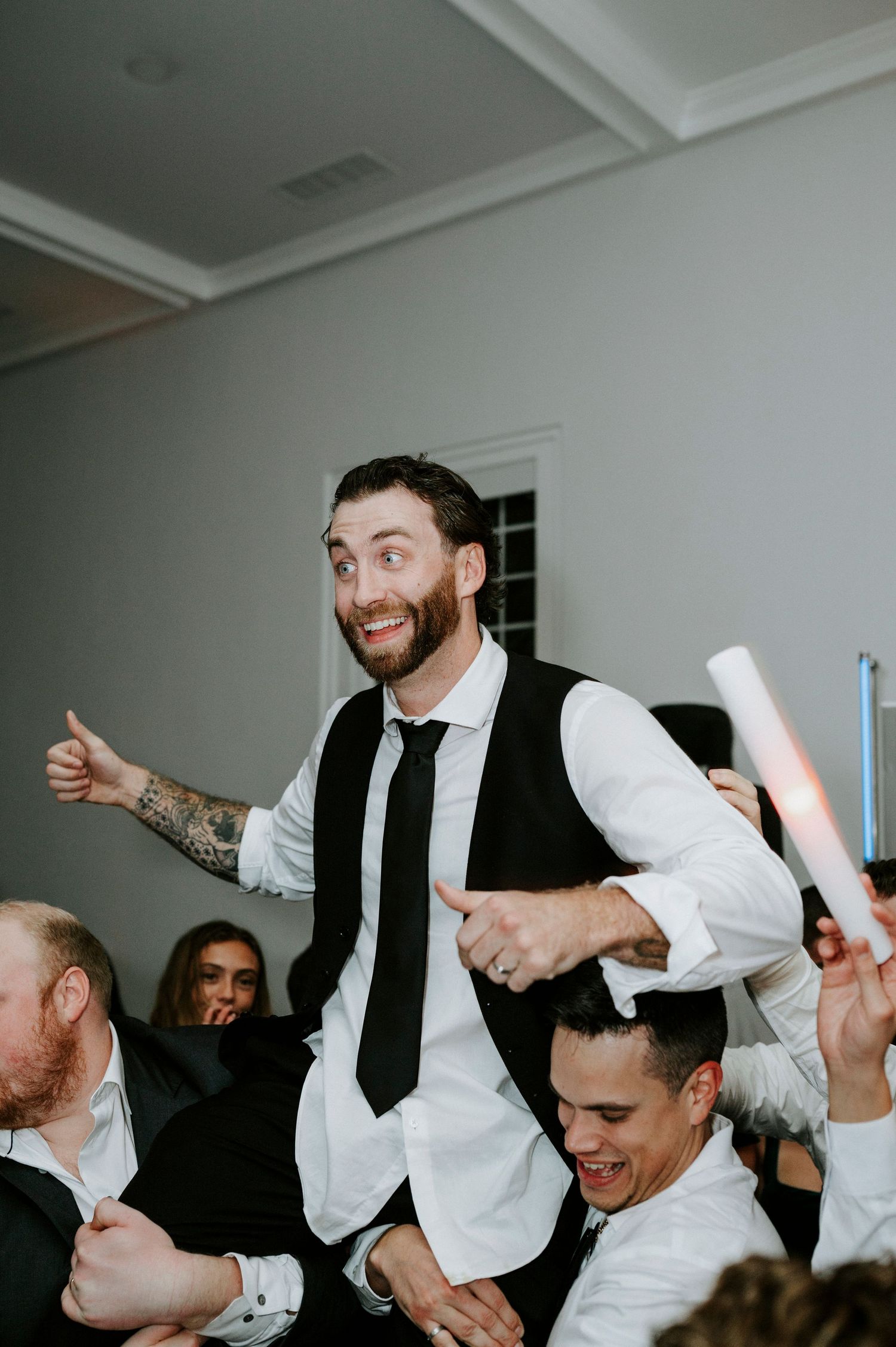 Energetic wedding celebration with guests dancing and jumping enthusiastically in formal attire.