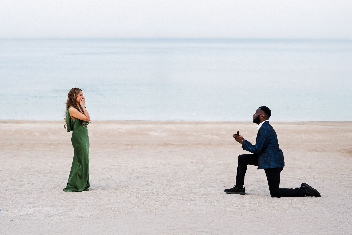 Surprise proposal photography in Dubai with groom kneeling on beach