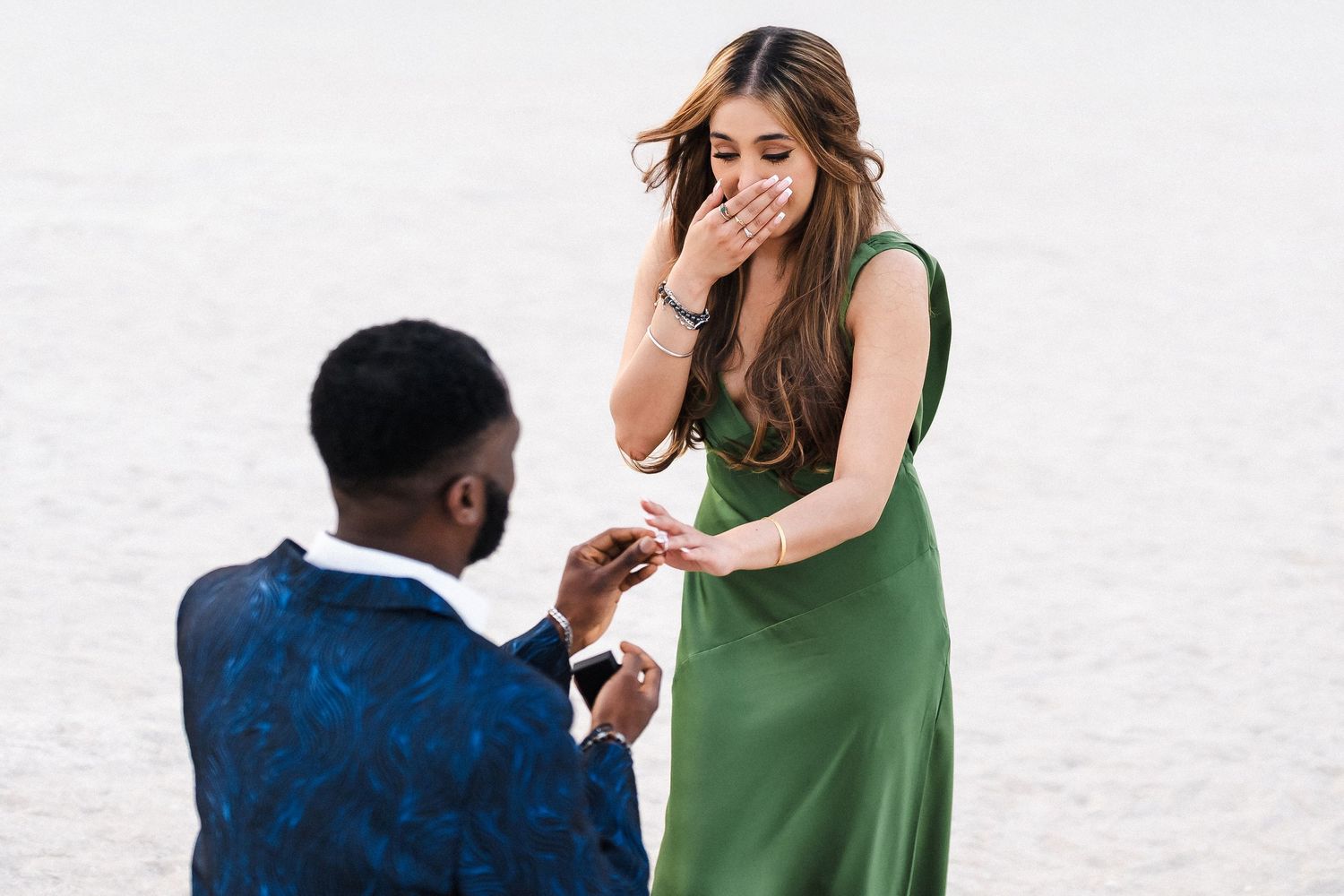 Surprise proposal photography in Dubai with groom kneeling on beach at sunset