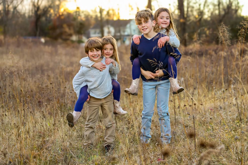 A group plays and runs together through a golden autumn field at sunset creating joyful candid moments.