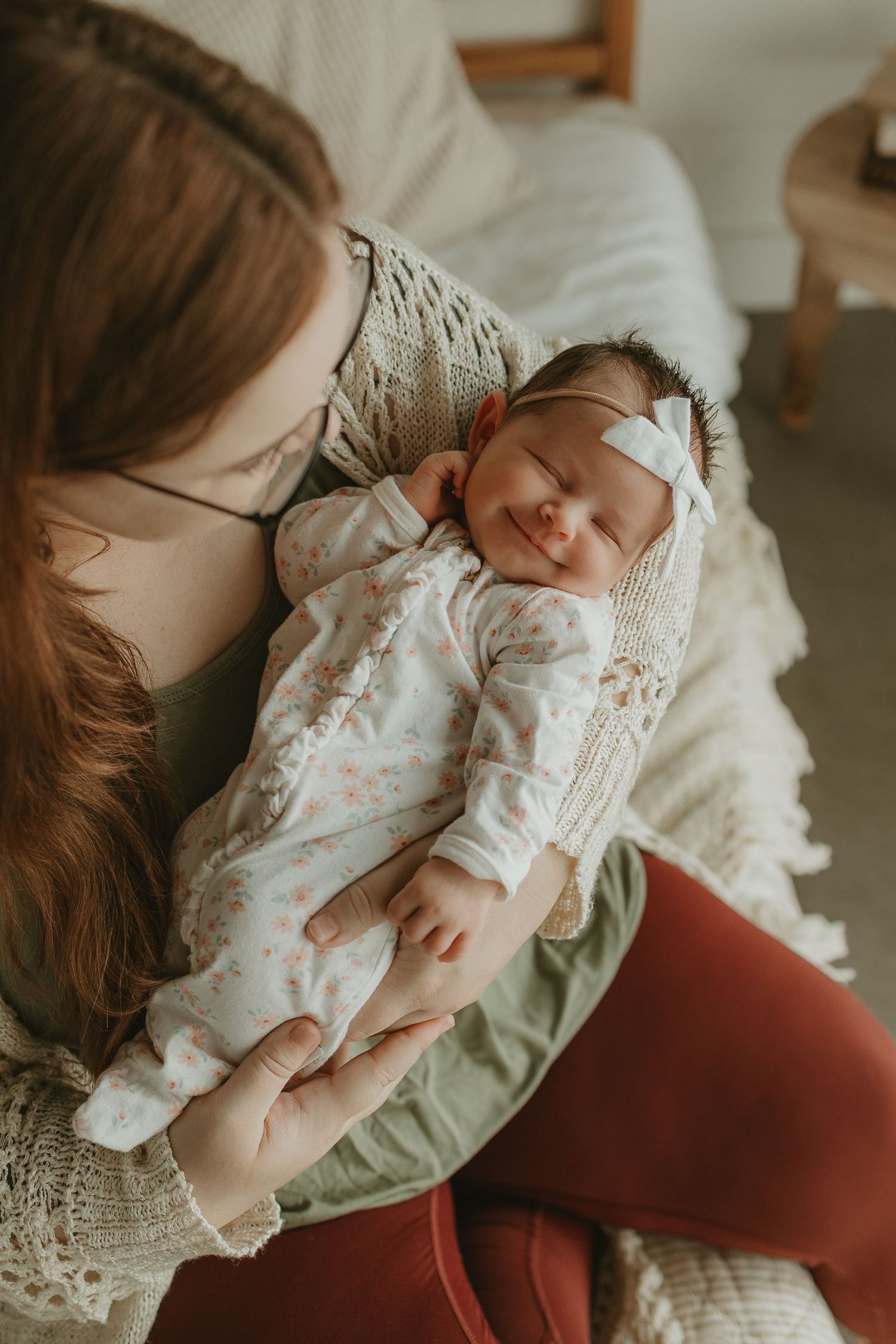 A tender moment between parent and newborn baby wearing white lace clothing against a soft neutral background.