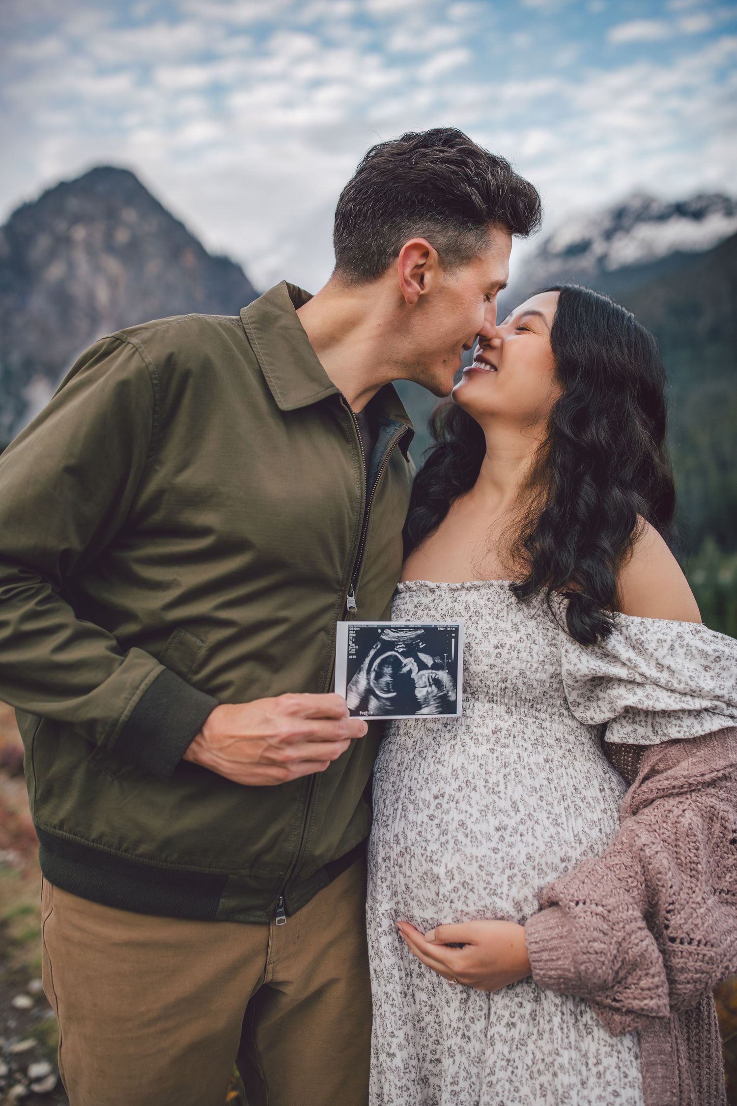 Couple kissing together and showing ultrasound during their adventure maternity photos in Snoqualmie, Washington