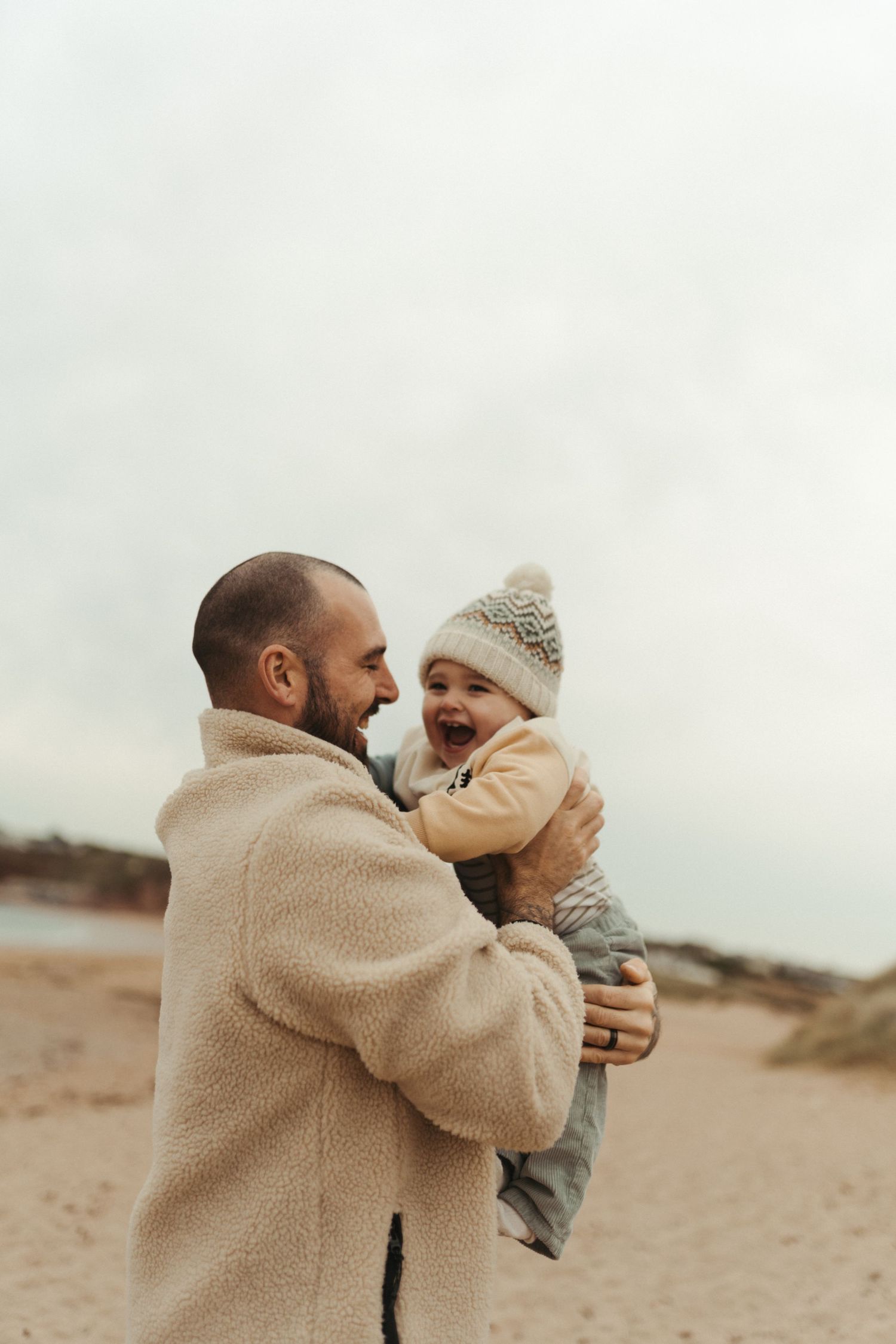 A tender moment shared between parent and child on a cloudy beach day.