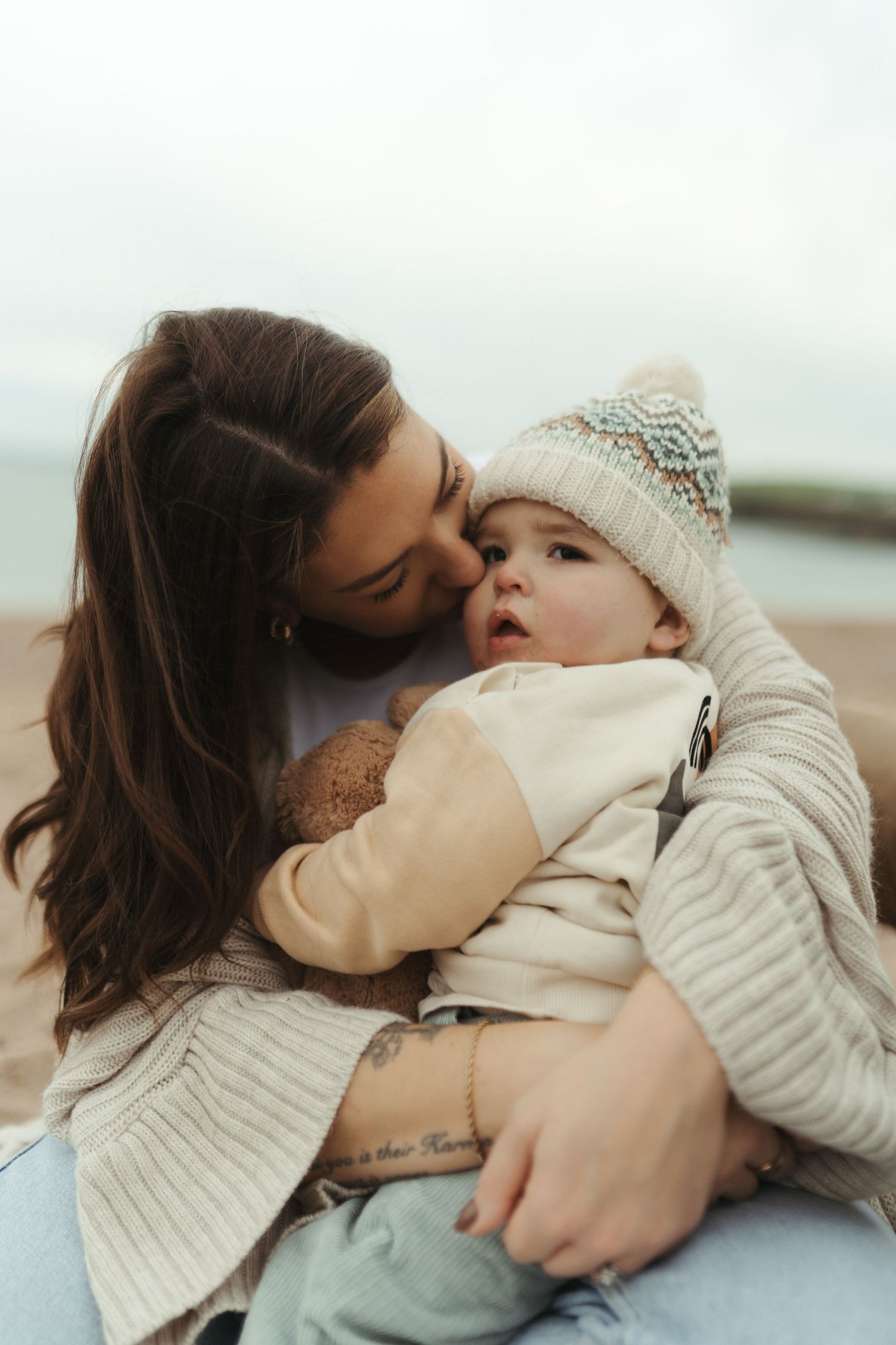 A sequence of gentle embraces between parent and child wearing cozy winter sweaters against a bright sky background.