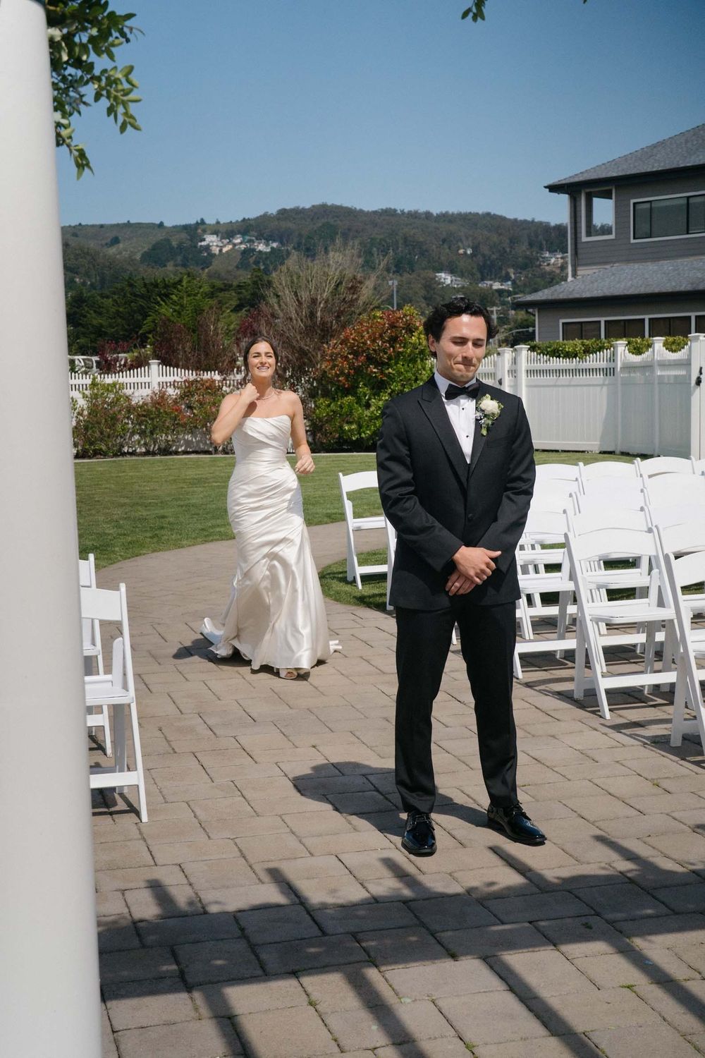 Outdoor wedding venue with white chairs and columns arranged on stone patio for ceremony.