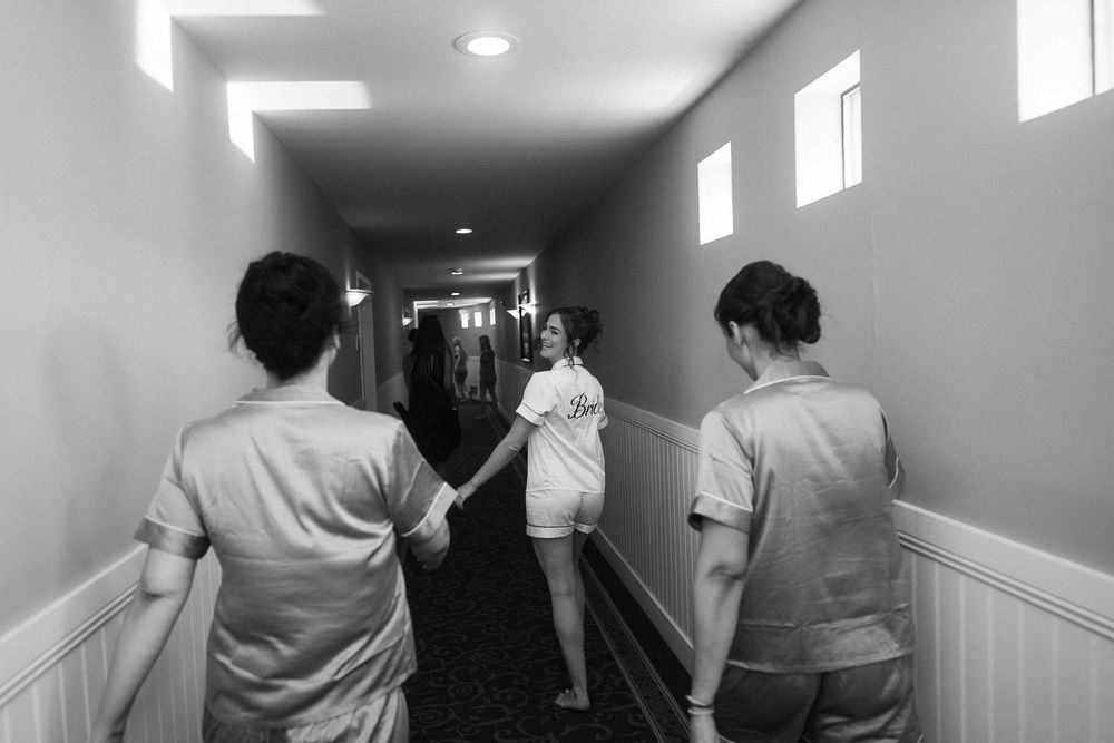 People walking through a dimly lit hallway with white walls and recessed lighting.
