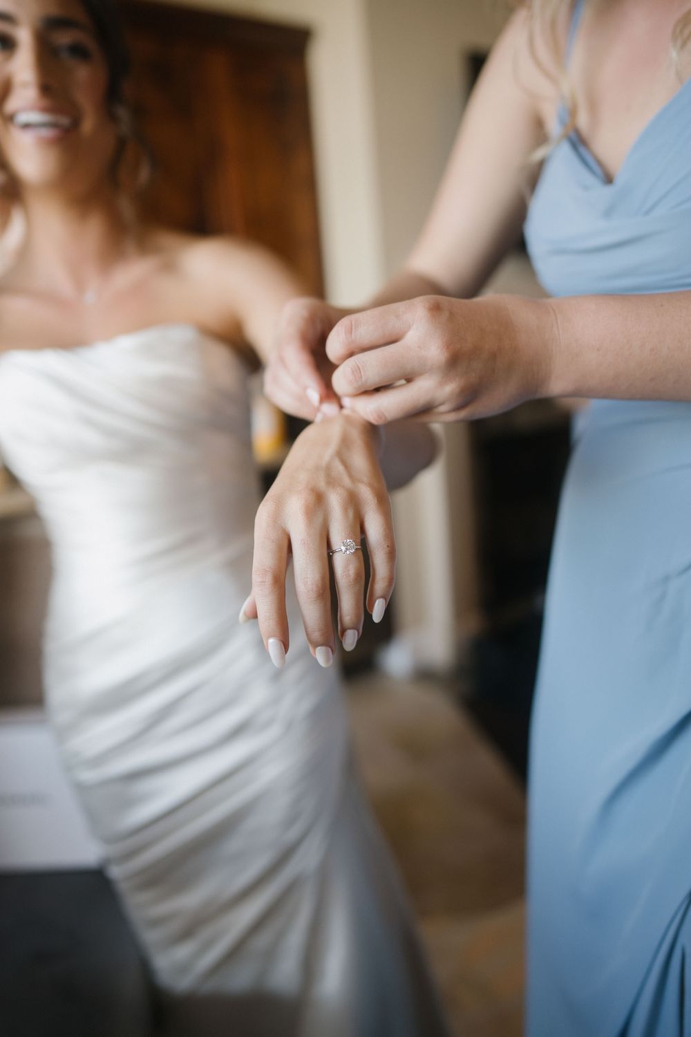 Close-up detail shots of a bride in white dress and bridesmaid in light blue dress during wedding preparations.