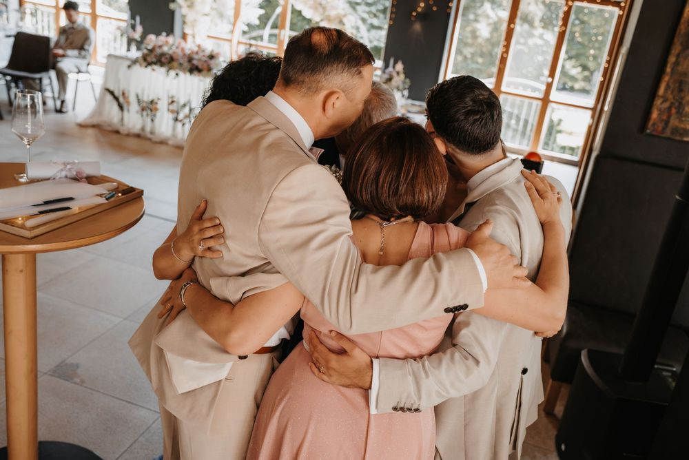 Group of four people sharing a warm embrace at an elegant wedding reception venue.