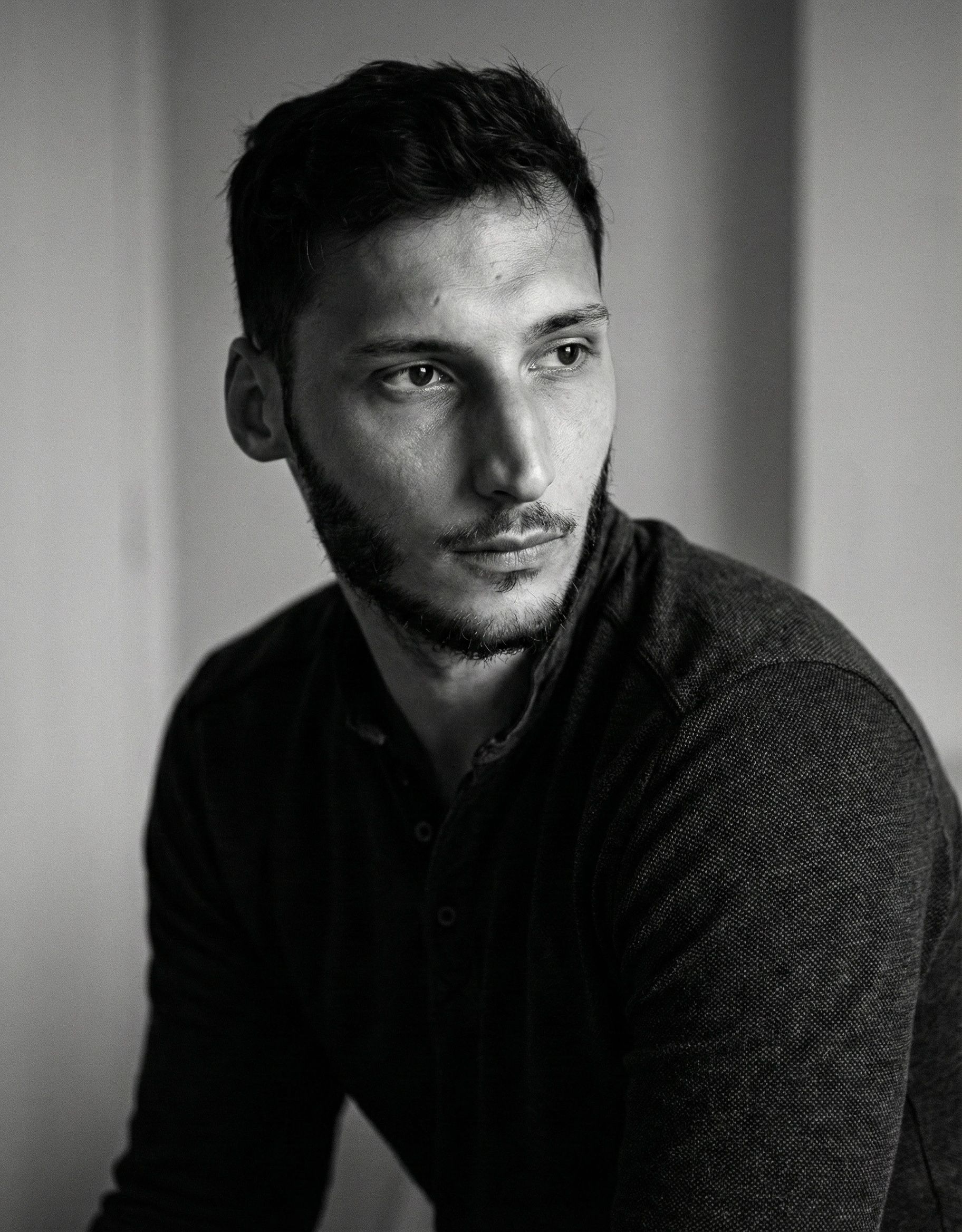 Black and white portrait series showing four moody profile shots of a person in dark clothing against a light background.