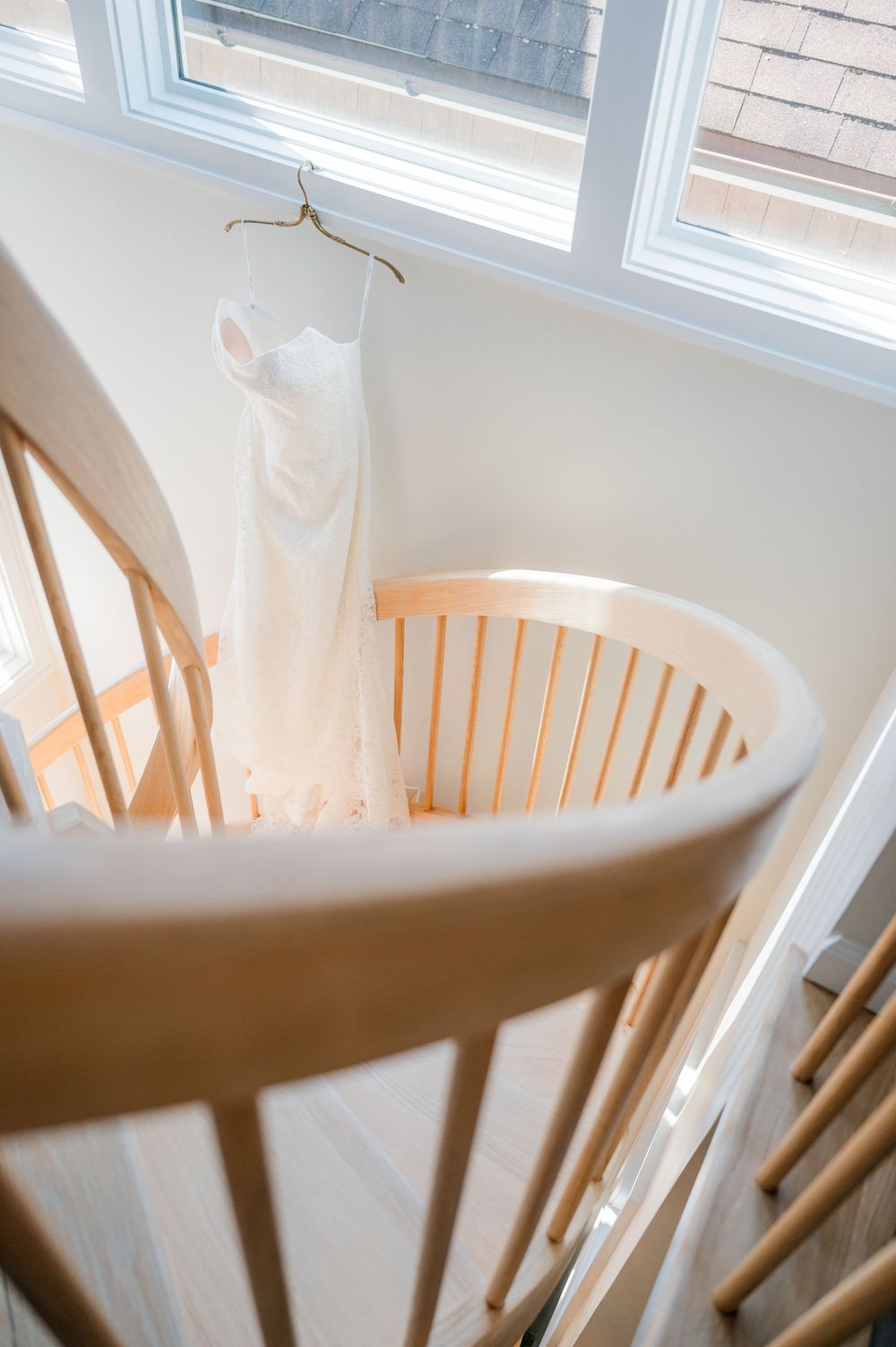 Curved wooden slats of a rocking chair or crib cast dramatic shadows against a white wall near a window.