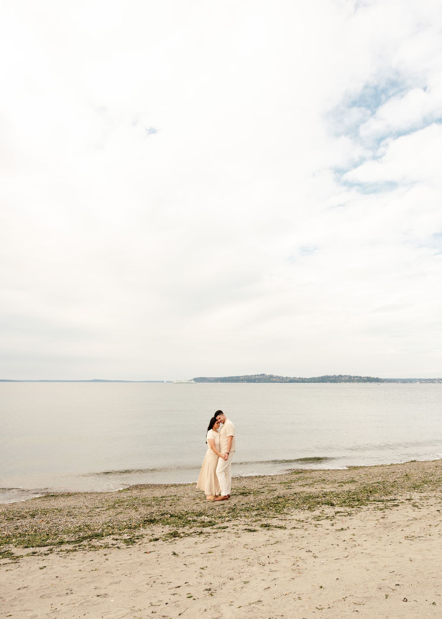 A panoramic view of a tranquil beach shoreline with sandy coast stretching into the distance on a cloudy day.