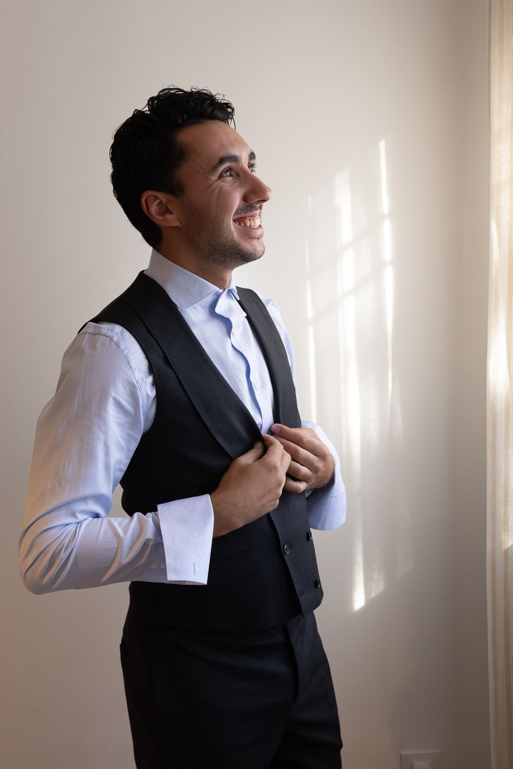 A sequence showing someone putting on a formal black vest over a white dress shirt.
