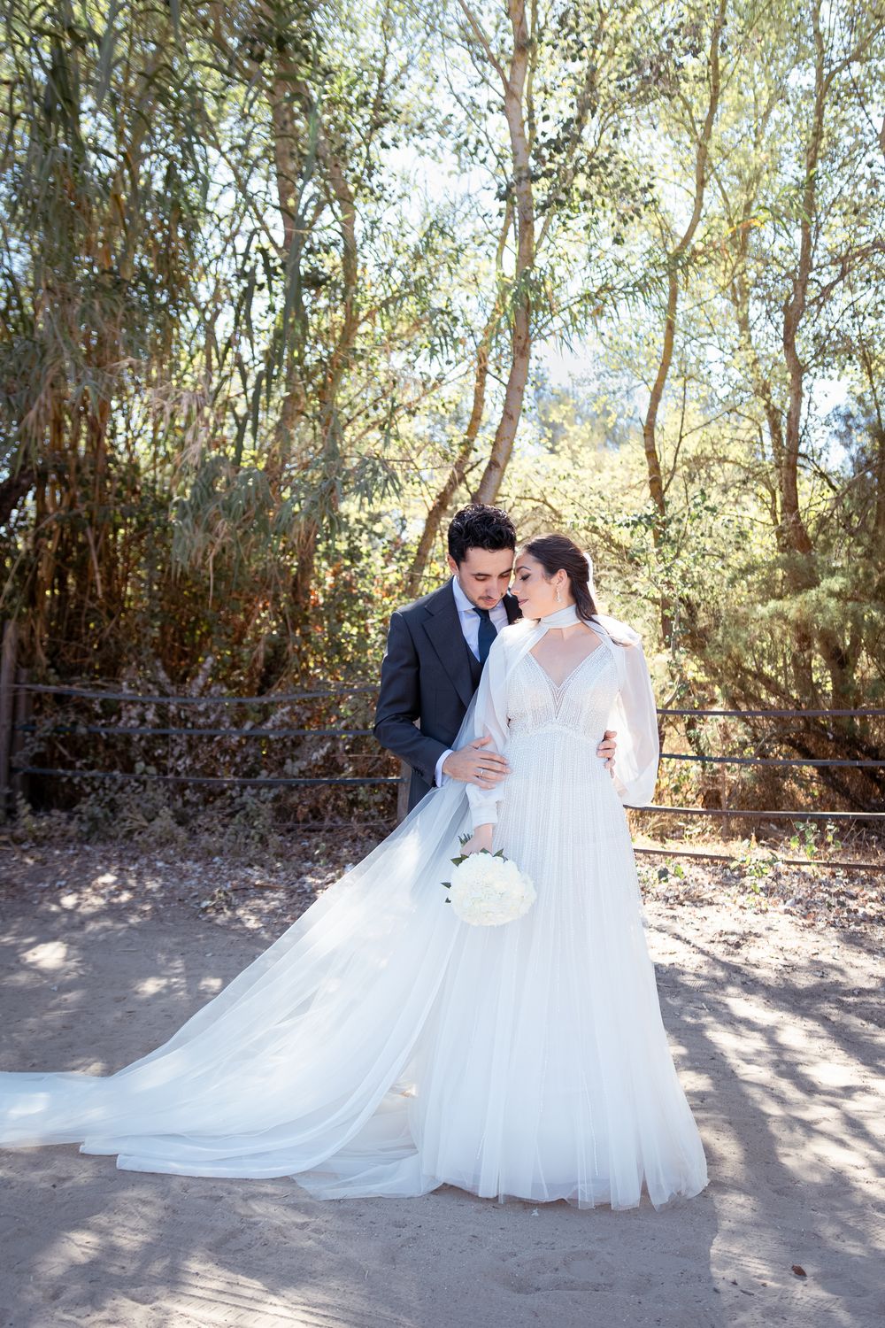 A romantic wedding photo series showing a couple in white dress and dark suit posing outdoors among trees.