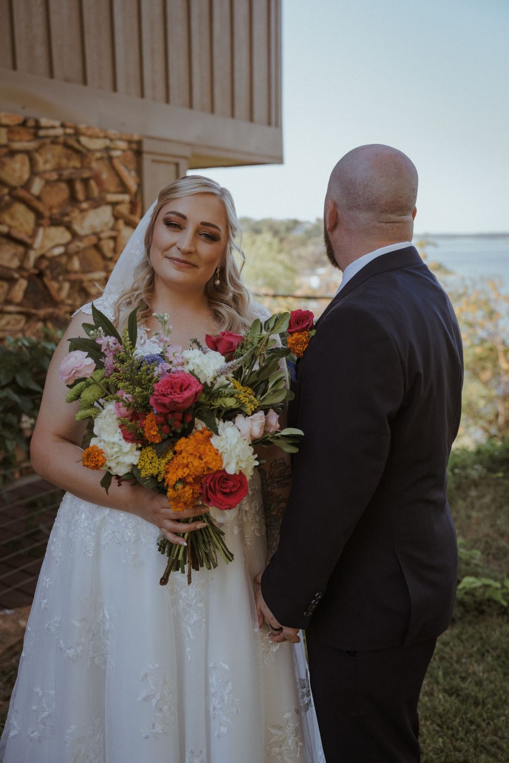 Outdoor wedding scene with colorful autumn bouquet and white bridal gown.